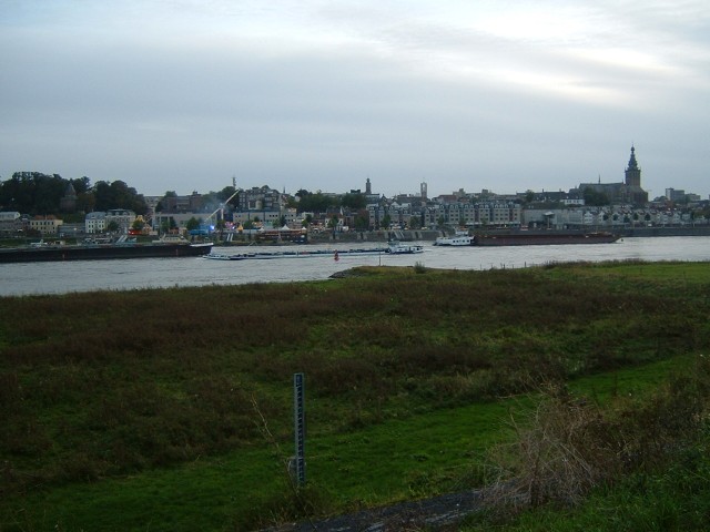 Nijmegen, with barges on the Rhine in the foreground and a funfair on the waterfront.