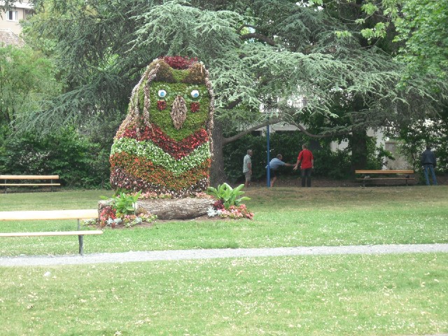 Is it an owl? Behind it are more people playing boules.