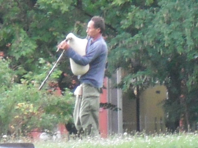 A man playing the bagpipes in the park.