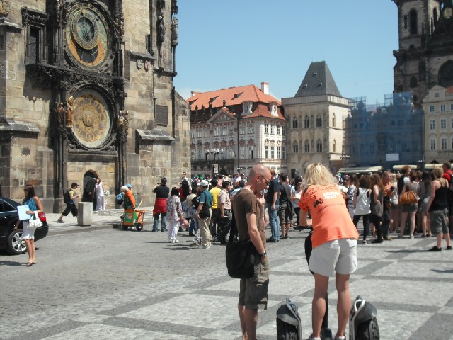 On the left, a bride and groom are having their photograph taken under Prague's Astronomical Clock.