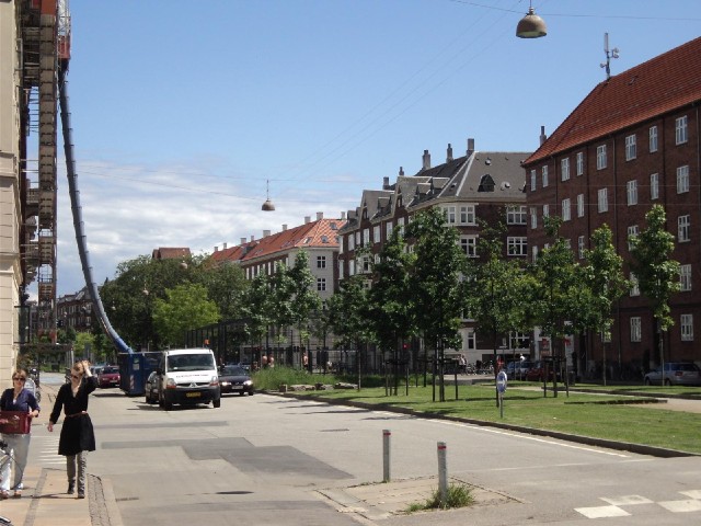 A wide boulevard in Copenhagen. The cycle lane runs under the rubbish chute, between the buildings a...