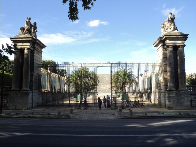 Another entrance into the grounds of the Palace of Versailles. What looks like a grey wall beyond th...