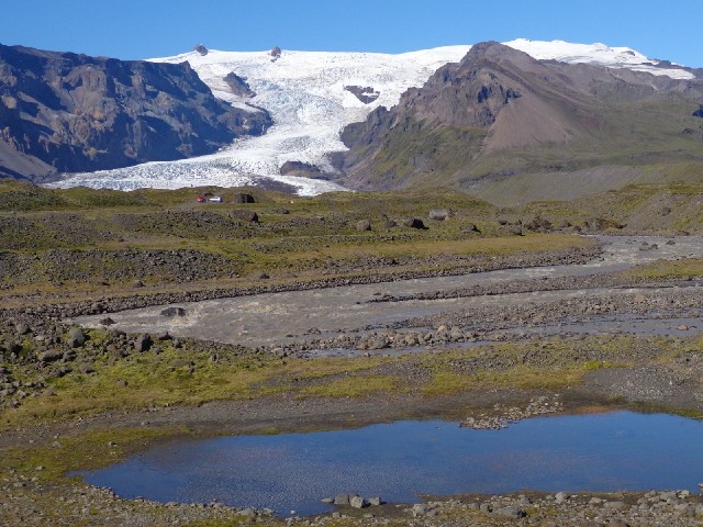 The glacial meltwater has a distinctive grey colour, unlike the water in the foreground.