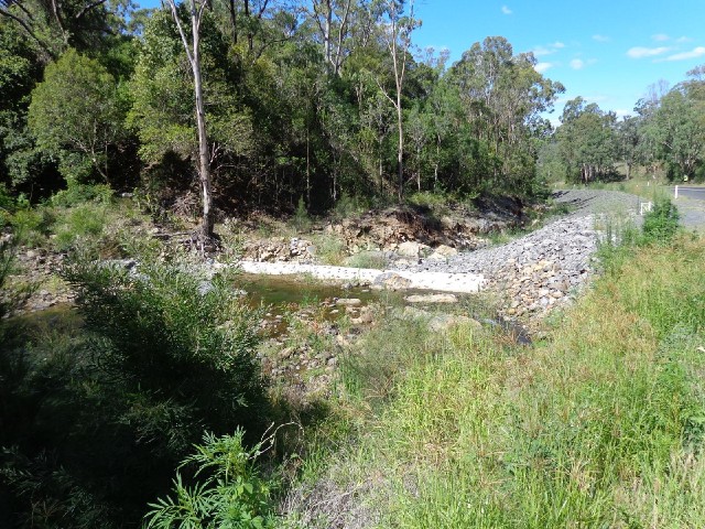 This stream has been dammed here so that it now turns and flows under the road. There is soil erosio...