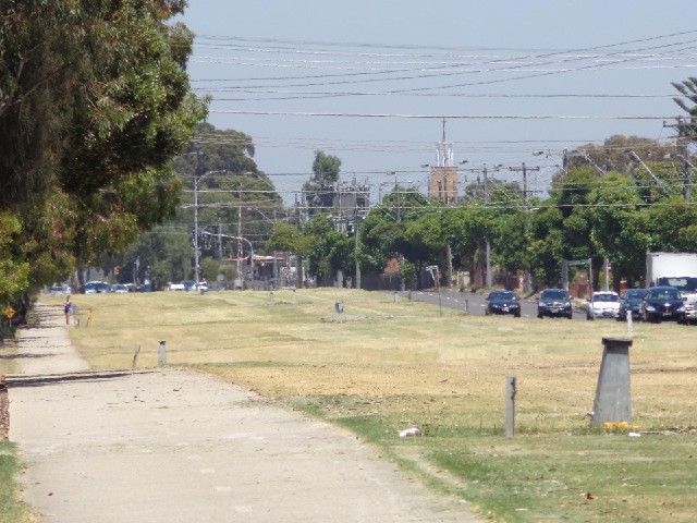A cycle lane along the wide grassy median strip of a road.