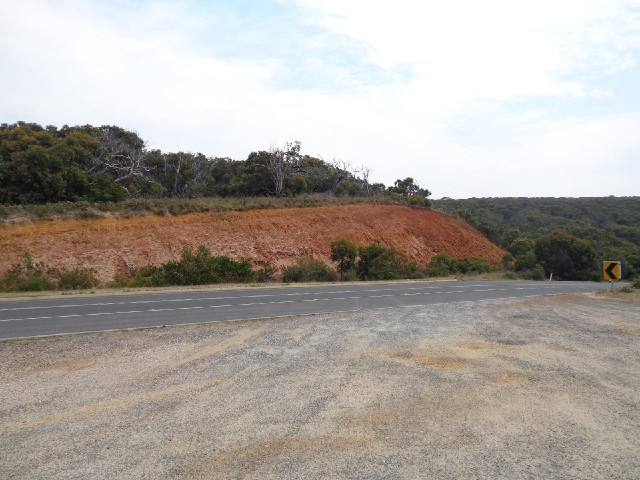 Exposed soil where the road has been cut through the hill.
