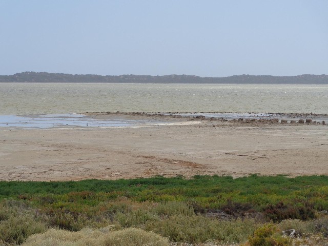 Part of a long muddy lagoon. The sea is beyond the spit of land in the disance.