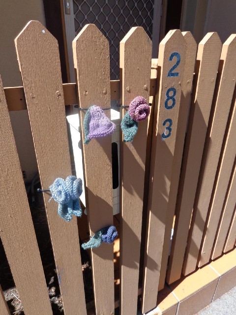 Knitted flowers on a gate.