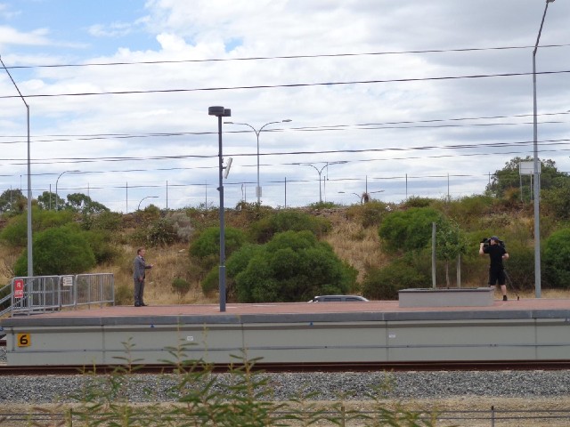 Two people making some kind of documentary film on the platform of one of the stations.