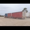 A road train kicking up some dust as it enters the car park.