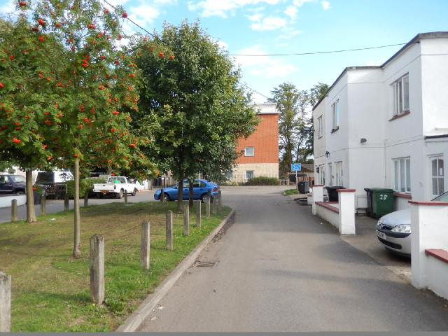 The ground is behind the block of flats ahead.