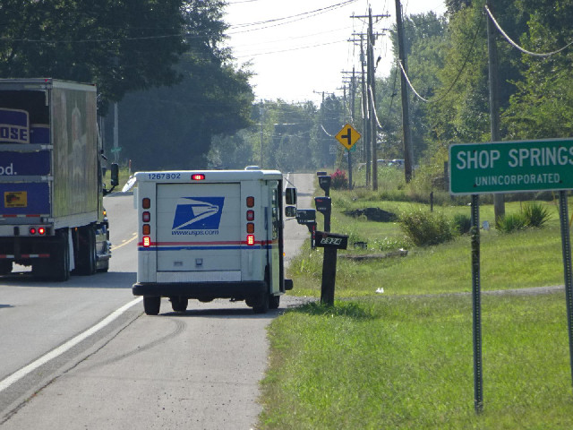 A Post Office van making a delivery to a mailbox.