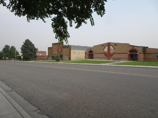 The building with the wooden front is the junior high school. The one with the circle on it says tha...