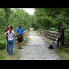 A film crew waiting for cyclists to come over the bridge.