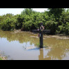 A cross in a flooded ditch next to the road.