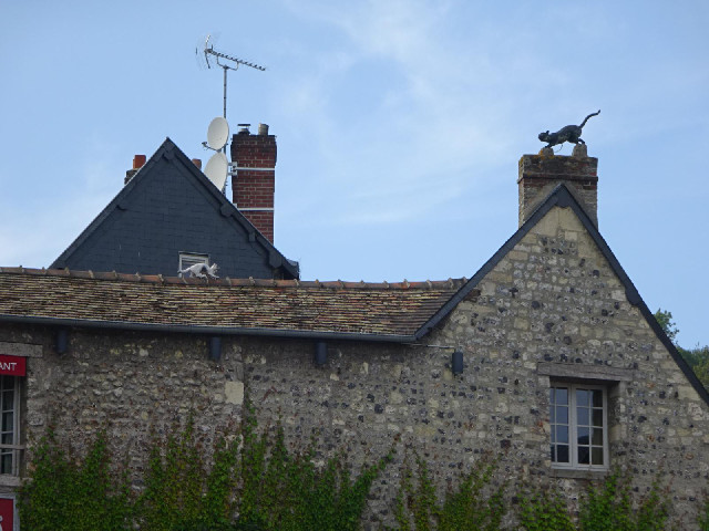 Statues of two cats on a roof.