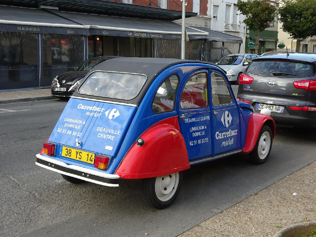 A 2CV parked outcide the supermarket which it advertises.