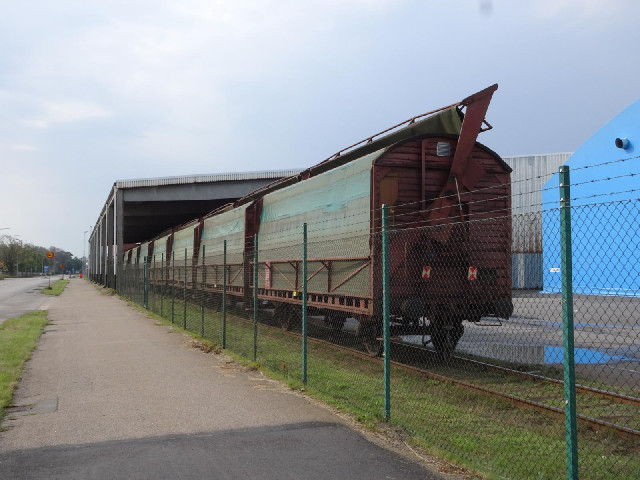 Some covered railway wagons in parked at a warehouse next to the harbour.