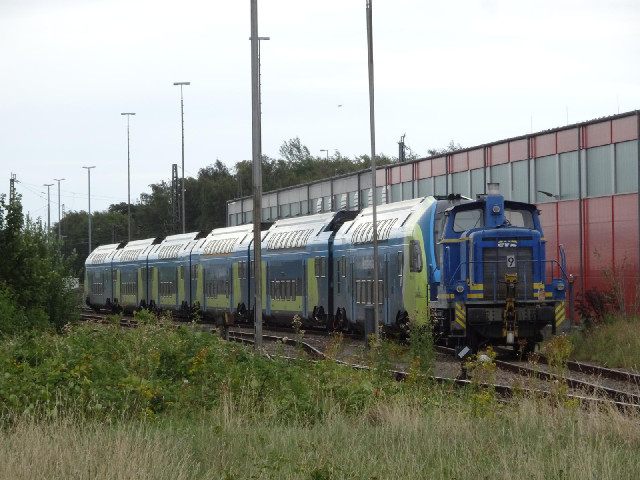 A double-decker train attached to a little shunting engine.