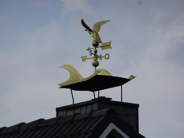 A fancy weather vane on a house.