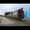 Some covered railway wagons in parked at a warehouse next to the harbour.