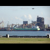 A ship being guided by tug boats at the front and back.