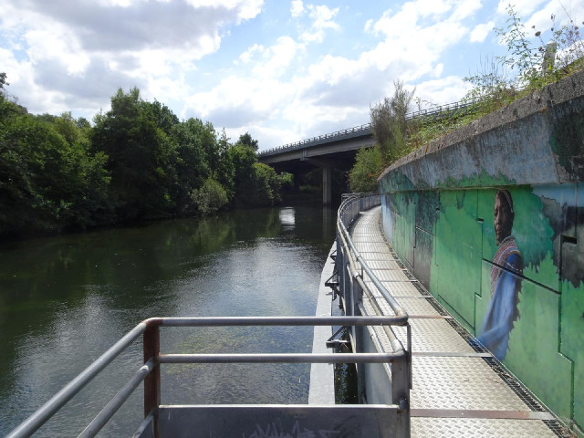 This metal bike path is mounted onto the side of a road and hangs over the river. It's only just wid...