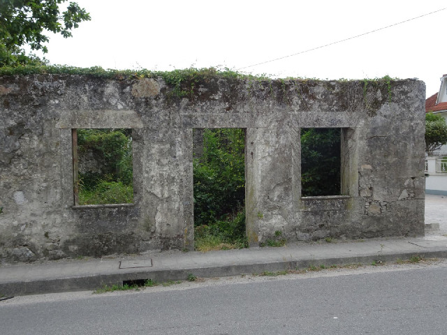 An abandoned house across the road from the sign.