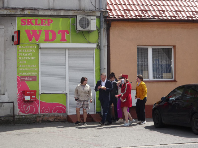 Here's a strange group of people. One of them is carrying a saxophone and two are eating cake.