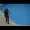 One of the hotel staff with something which he has just fished out of the pool.