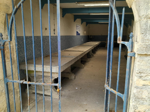 An unlocked room under the town hall contains this row of old  stone tables with what look like drai...